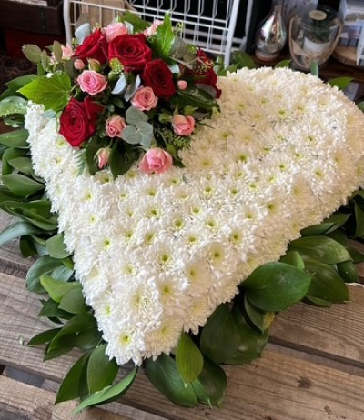 Heartfelt Rose Tribute - An elegant heart-shaped funeral tribute in classic white, beautifully finished with a cluster of rich red and soft pink tones.