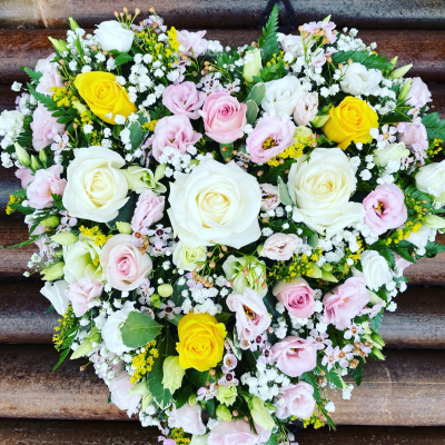 Gentle Heart Tribute - A beautiful heart-shaped funeral tribute arranged in soft pink, white and cheerful yellow tones, creating a warm and heartfelt farewell.
