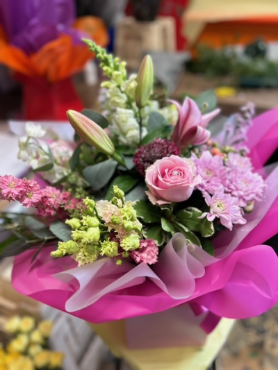 Petal Kiss - A beautiful arrangement of soft pinks and fresh greens, finished with elegant foliage and vibrant pink wrapping.