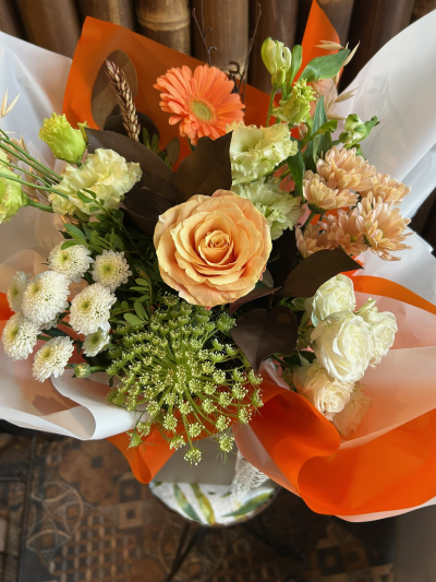 Amber Glow - A warm and vibrant bouquet of peach, orange and cream blooms, beautifully complemented by fresh greenery.