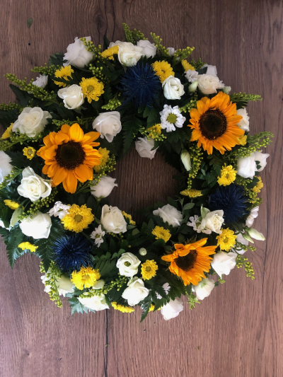 Golden Sun Wreath - A vibrant funeral wreath featuring sunny yellow, crisp white and deep blue blooms, finished with fresh greenery.