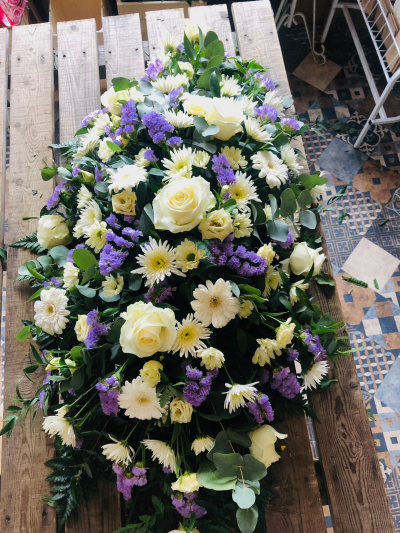 White & Purple Spray - A graceful funeral spray of soft cream and lilac blooms, beautifully arranged amongst fresh greenery.