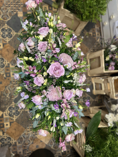 Lilac Serenity Spray - An elegant funeral spray featuring soft lilac and purple blooms, delicately arranged with fresh greenery.