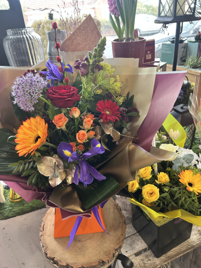 Vivid Delight - A bold and colourful bouquet bursting with vibrant orange, red and purple blooms, beautifully finished with lush greenery.