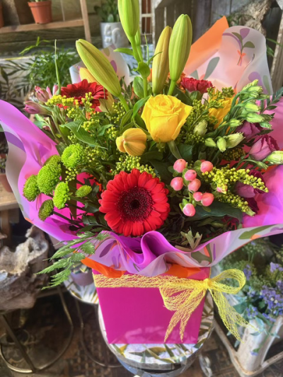 Berry Bright - A vibrant bouquet bursting with bold red, yellow and pink blooms, beautifully complemented by fresh greenery.