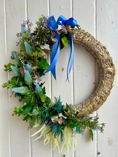 Blue Botanical Wreath - A contemporary decorative wreath featuring natural greenery, soft blue accents and a striking blue ribbon.